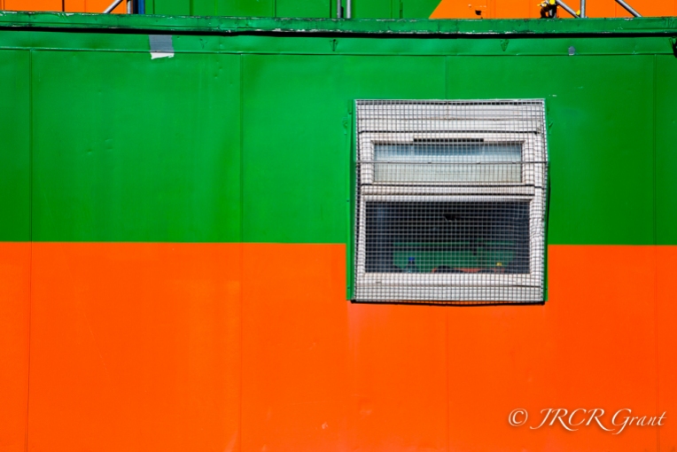 Window set into a bright portakabin of orange and green,