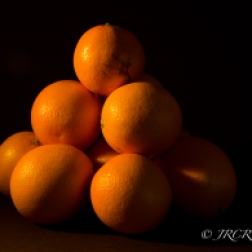 Oranges piled up with sun dancing on them