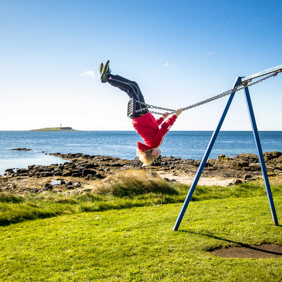 A young man flies high on a swing on the island of Arran